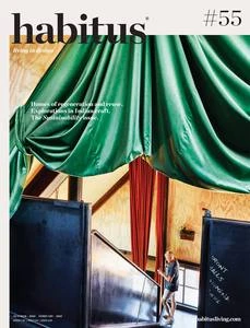 Cover of Habititus Living Magazine featuring a woman walking up the stairs under a green curtain, focusing on interior design.