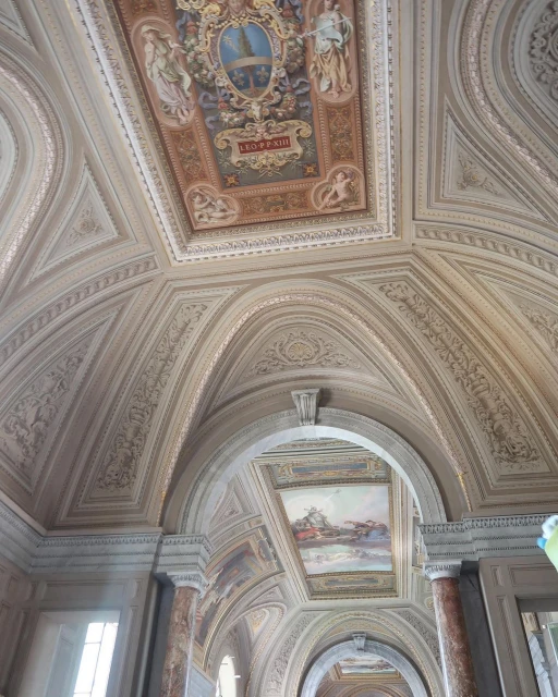 Ornate interior architectural view featuring decorative ceilings with paintings, arches, and columns, in an indoor setting, enhancing the space.