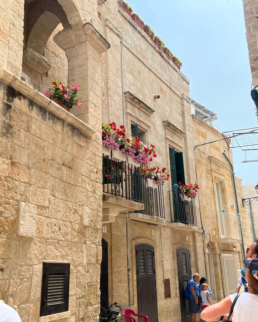 Charming European street scene featuring stone buildings adorned with colorful flower boxes, creating a vibrant and picturesque atmosphere.