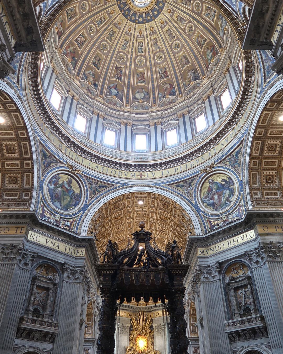 Intricate architecture of St. Peter's Basilica dome features paintings, windows, and ornate carvings, creating a visually stunning interior view.