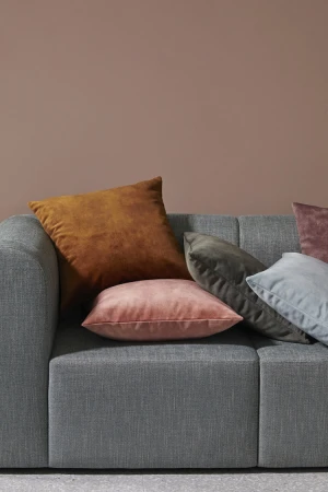 Grey couch with a collection of decorative pillows in shades of brown, pink, grey, and blue, creating a cozy and inviting interior scene.