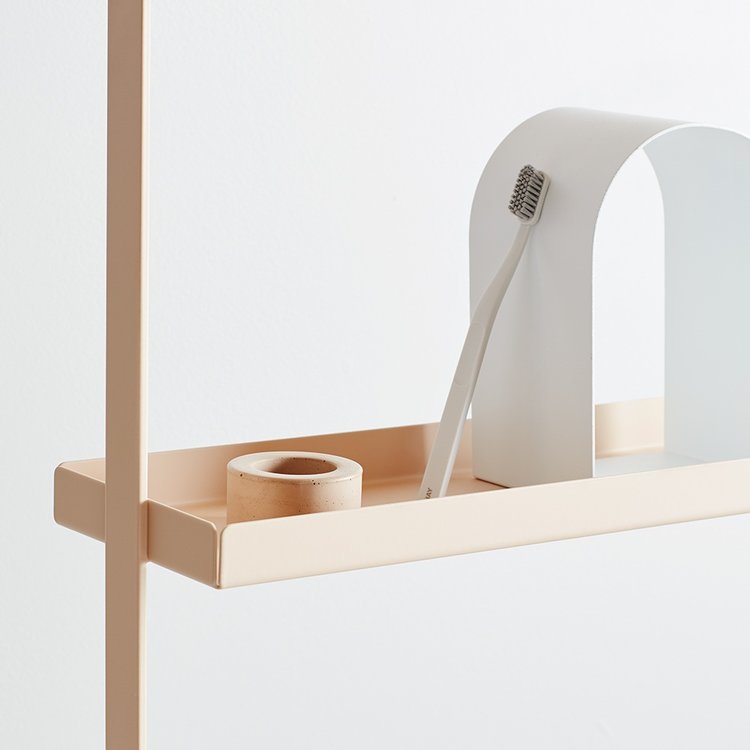 Minimalist peach-tone shelf featuring a toothbrush, decorative arch, and small vessel against a clean white background, creating a serene aesthetic.