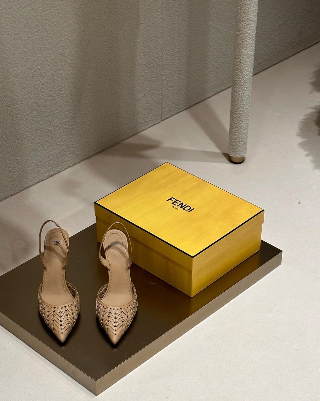 Elegant slingback shoes by Fendi are displayed on a brown surface, along with a Fendi box, in a clean, well-lit indoor space.