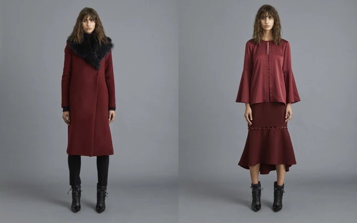 Two adult females wear fashionable burgundy overcoats and skirts in a studio with a gray background, complemented by black ankle boots.