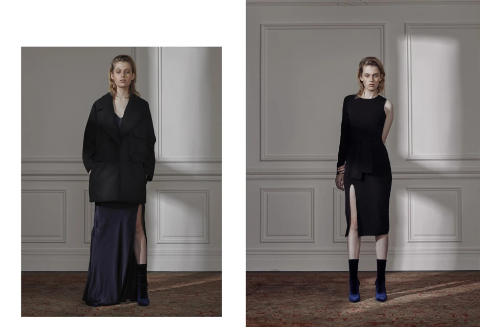 Two fashion models pose indoors on a carpet, wearing black dresses and blue boots in a fashion editorial shot with soft, natural lighting.