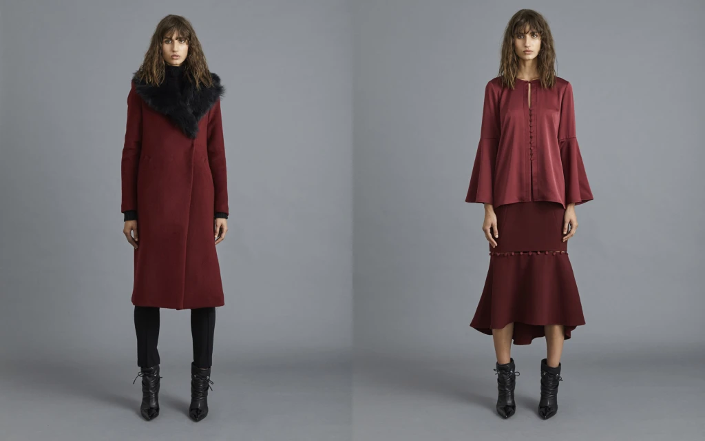 Two fashion models showcase deep red apparel, including a coat with a fur collar and a flared-sleeve blouse with a matching midi skirt.