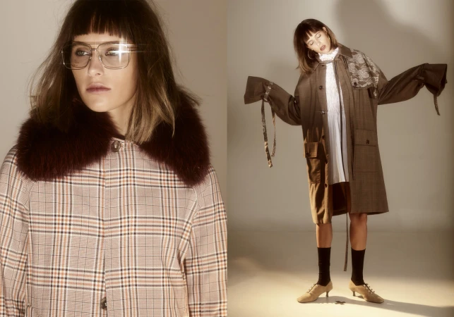 Two women in studio shot, one in a plaid coat with a fur collar and glasses, the other in a long brown coat with white dress.