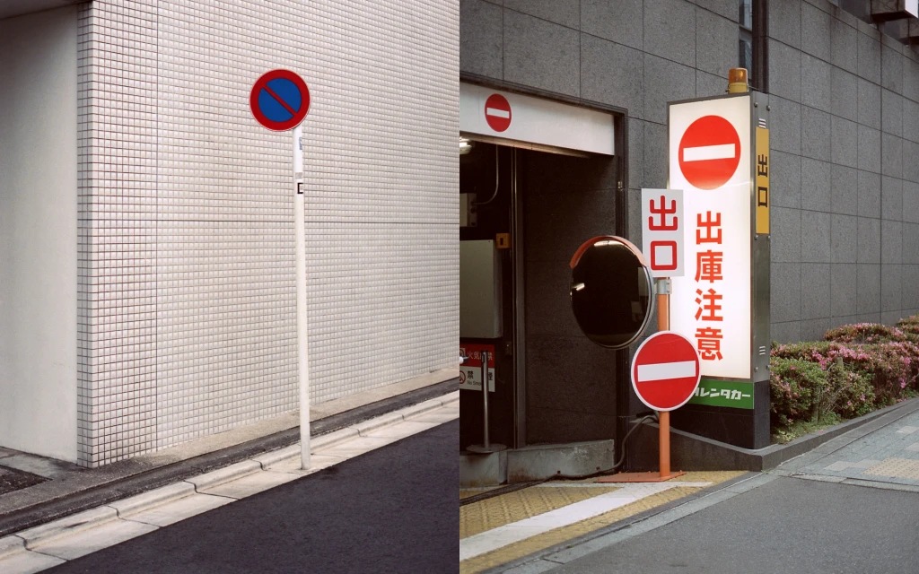 Street scene featuring various traffic signs with white buildings and grey paved road, creating a visually structured urban landscape.