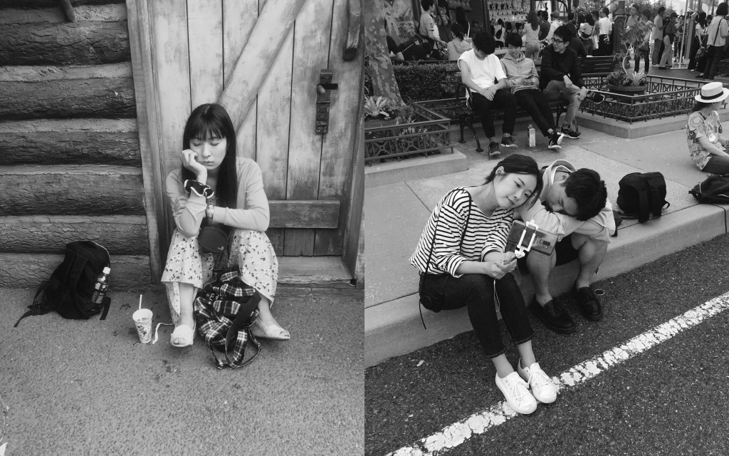Monochrome shot of woman seated by wooden door, couple resting on curb, and people seated on benches in an outdoor urban setting.