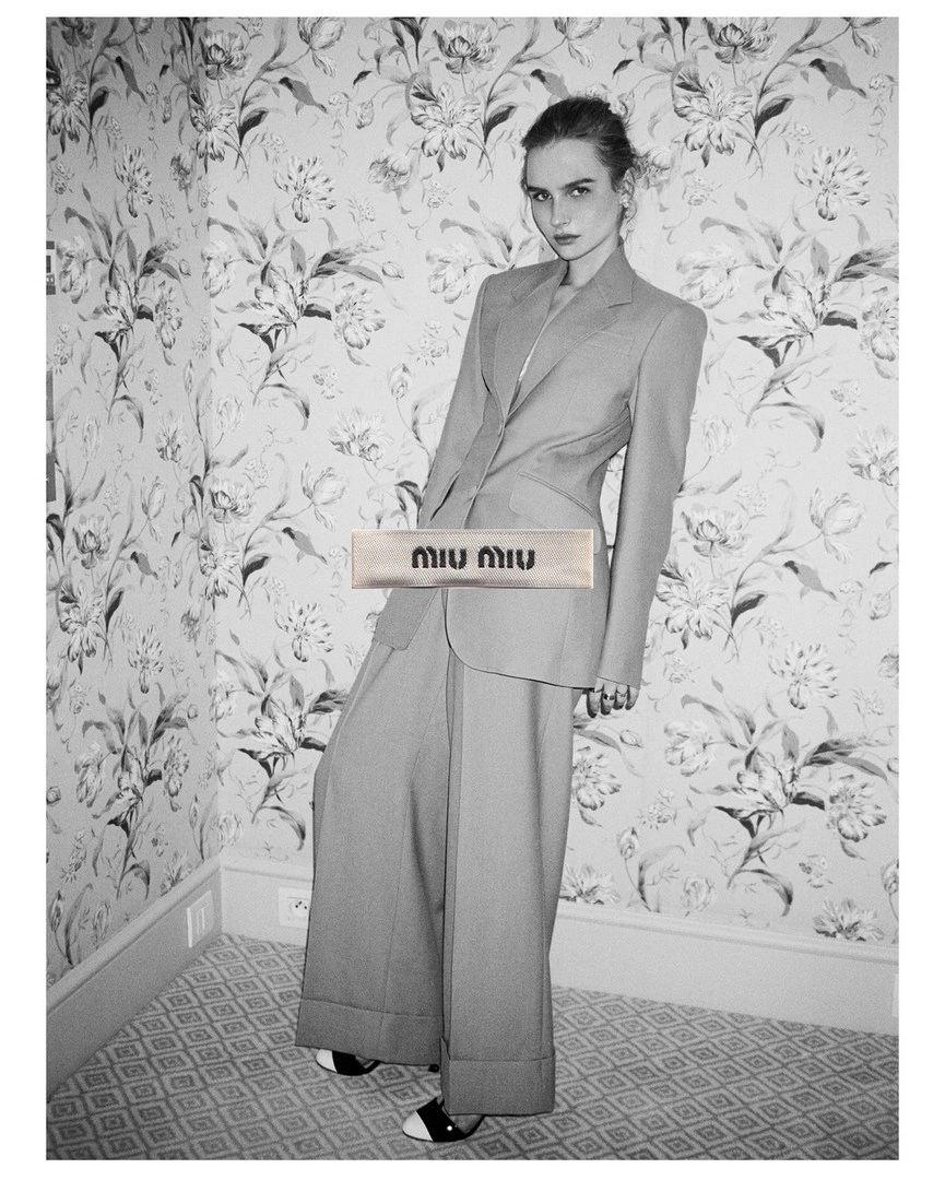 Model in tailored pantsuit posing in a patterned wallpaper room by Jess Ruby James
