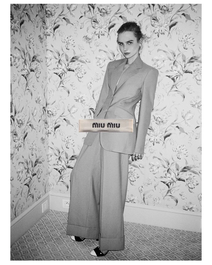 Model in tailored pantsuit posing in a patterned wallpaper room by Jess Ruby James
