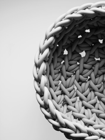 Close-up black and white image of a woven basket with thick, interlocking strands forming the side of the basket against a plain background.