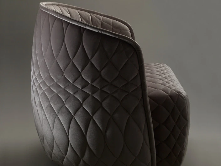 Close-up of a grey quilted armchair with a modern design. The quilted pattern is diamond-shaped, creating a plush, textured appearance.