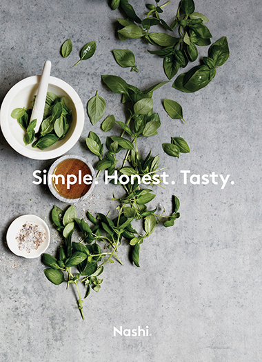 Overhead shot of fresh basil leaves arranged with small bowls of ingredients on a gray textured surface, alongside the text 'Simple. Honest. Tasty.'