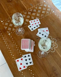 Playing cards and two wine glasses filled with sparkling wine arranged on an inlaid wooden coffee table.