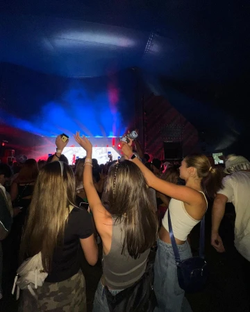 Enthusiastic crowd enjoys live music in a concert setting. Attendees raise arms, bathed in blue and red stage lighting at a music event.