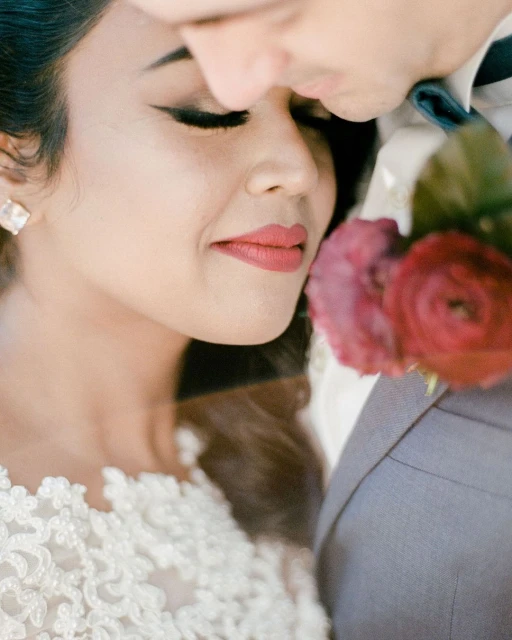 Close-up shot of a happy bride next to a groom, floral detail, romantic wedding moment, and shallow depth of field.