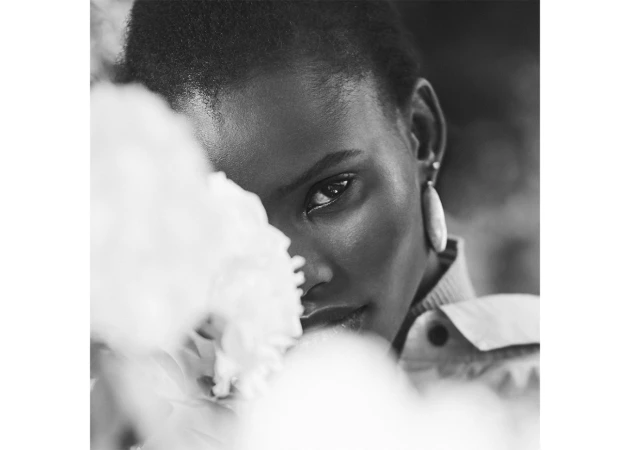 Monochrome portrait of a Black woman partially obscured by out-of-focus white flowers, photographed in Sydney by Isa Sanchez.