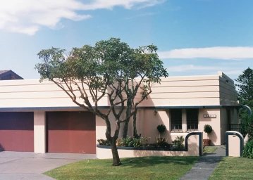 Modern single-story house exterior in Sydney with a light pink facade, dark red garage doors, and a small front tree by Isa Sanchez.