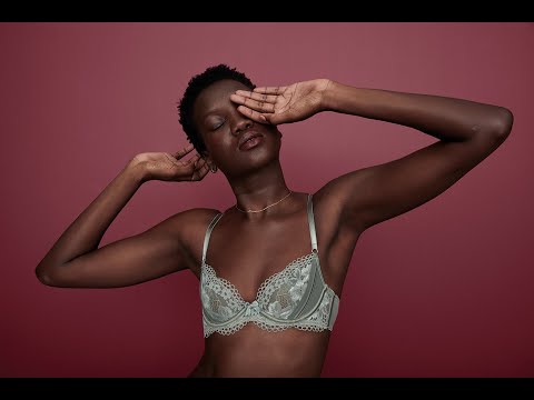 Close-up of an African-American woman with short hair wearing a lace bra with a deep red backdrop, fashion, and beauty aesthetic.
