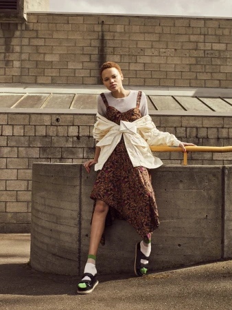 Model with short red hair wearing a patterned midi dress and white jacket styled by Jade Leung in Sydney