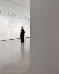 Content creator Jai Waetford standing inside a brightly lit art gallery exhibition space with polished concrete floors.
