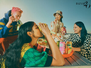 Four people gathered at a picnic table outside, enjoying drinks and snacks, under a bright sky, fashion shot, Bazaar logo visible.
