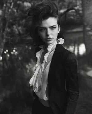 Monochrome portrait of a woman with voluminous dark hair wearing a ruffled blouse and dark blazer, styled by Jana Pokorny.