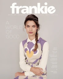 Magazine cover portrait of a female model with a braided hairstyle wearing a patterned purple and white dress against a plain grey backdrop.