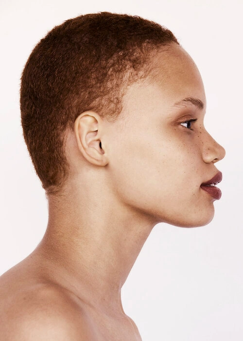 Profile portrait of a woman with short brown hair and makeup by Jasmin Lo against a plain white background