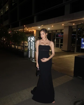 Woman in a black spaghetti strap evening gown standing outside a venue at night in Sydney by Jayde Heiser.