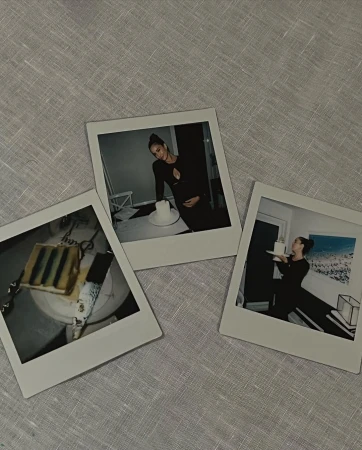 Three Polaroid prints show a pregnant woman and cake, on a linen tablecloth, capturing a celebratory, intimate moment in a neutral setting.
