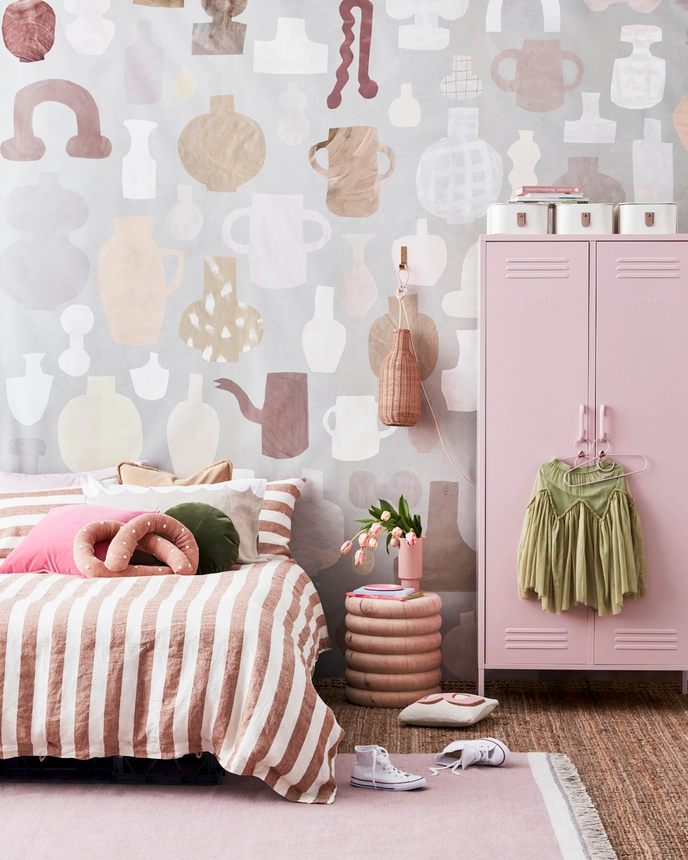 Pink bedroom interior styled by Jessica Hanson featuring vase-patterned wallpaper, pink locker, and striped bedding