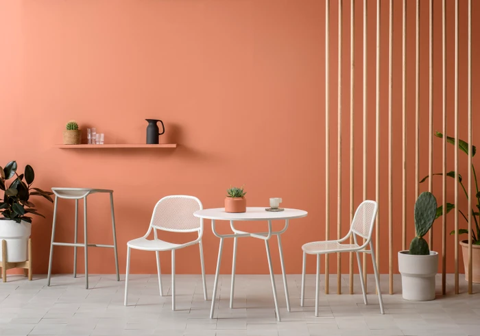 Minimalist interior with white table, chairs, bar stool, and terracotta wall styled by Jessica Hanson