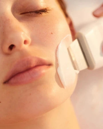 Adult woman with closed eyes receiving cosmetic facial treatment from professional, close-up shot, healthcare and beauty concept.