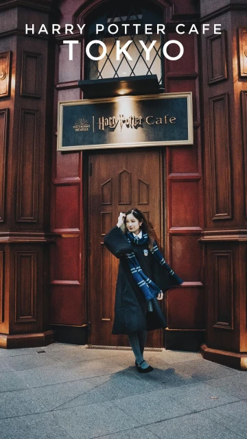 A young woman in a Harry Potter robe stands in front of the Harry Potter Cafe in Tokyo, Japan, on a cloudy day.