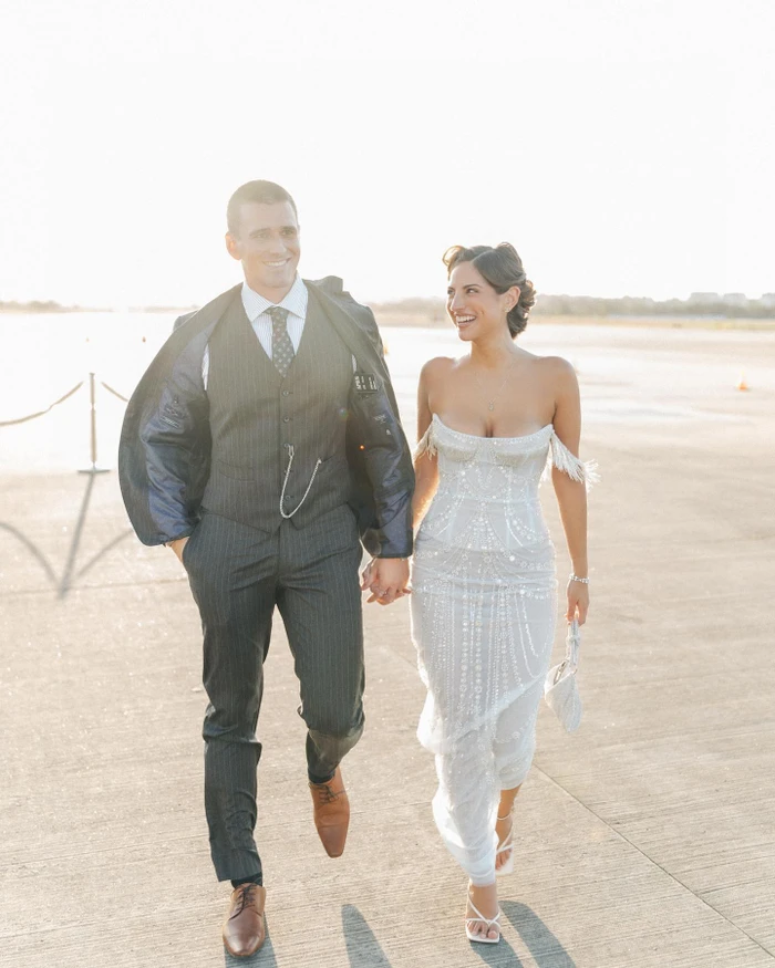 Man in dark pinstripe suit and woman in white strapless gown walking together outdoors in Sydney
