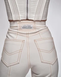 Close-up of cream high-waisted trousers with contrast topstitching and a Lilian Khallouf brand label on the waistband.