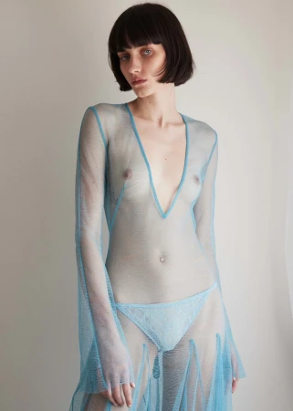 Model with dark bob haircut wearing a sheer light blue mesh dress against a neutral background