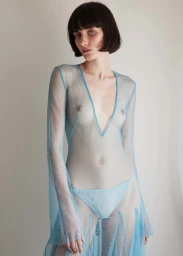 Model with dark bob haircut wearing a sheer light blue mesh dress against a neutral background