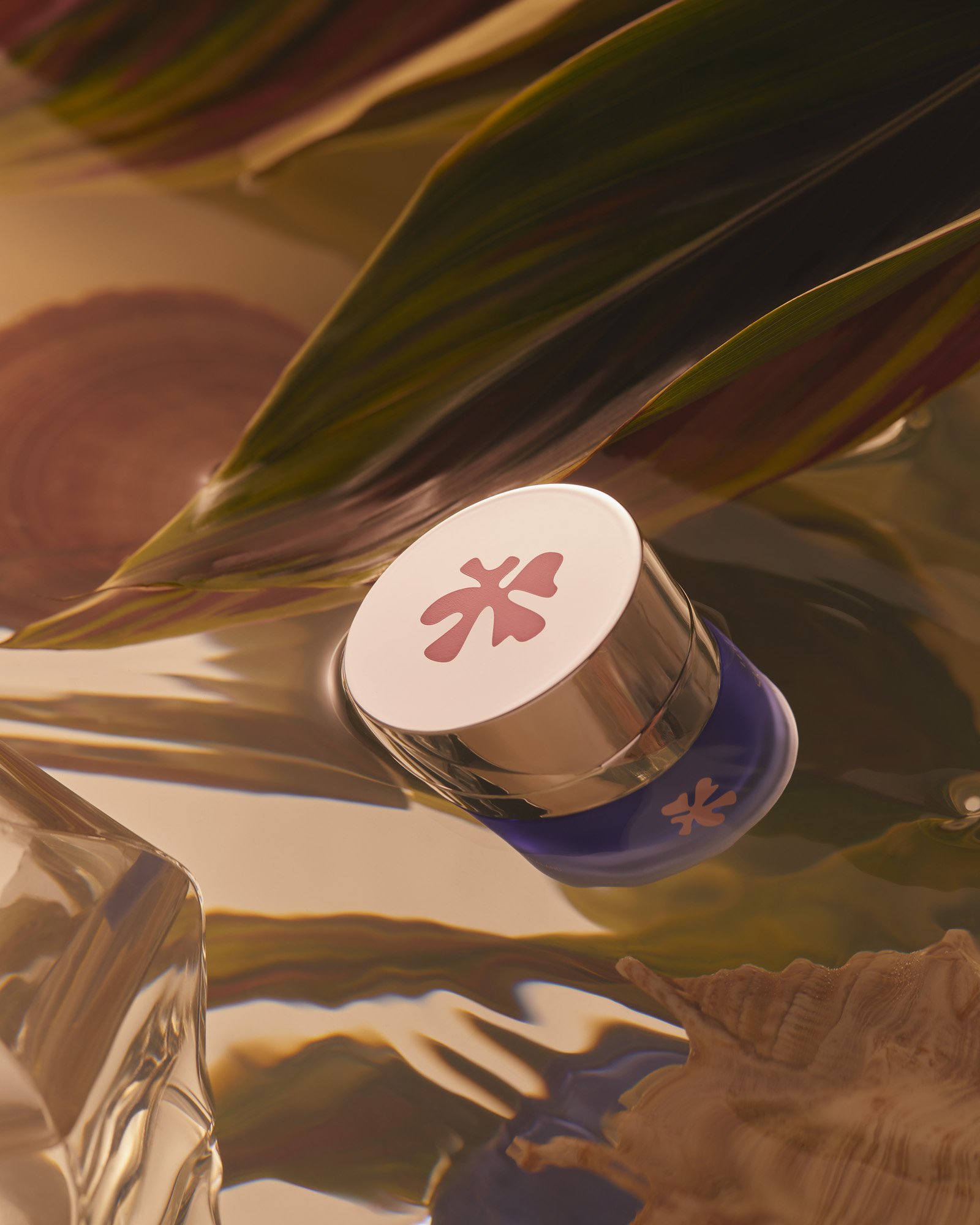 Eye cream jar in a beauty still life featuring a blue and white container with gold trim, against a fluid, reflective background.