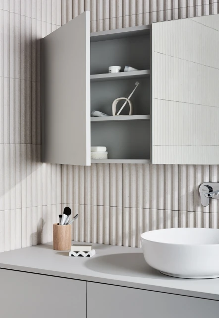 Bathroom interior featuring a white vessel sink, grey vanity, and open medicine cabinet with bathroom supplies against a textured wall.