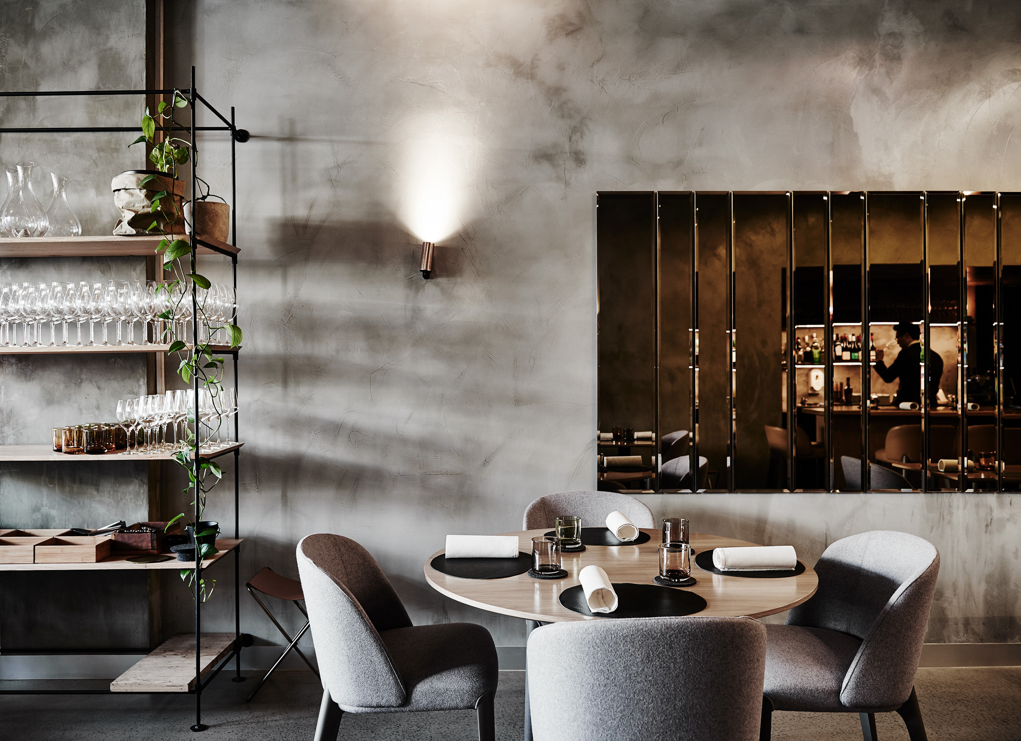 Elegant dining room with modern decor featuring a table set for four, stylish chairs, and a mirrored wall in a sophisticated restaurant.