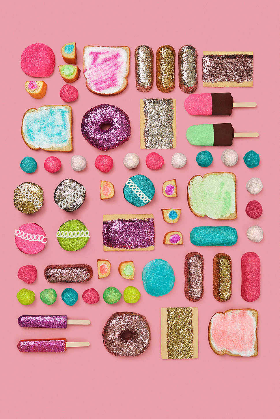 Overhead shot of colorful glitter-covered doughnuts, cakes, candies, and toast arranged on a pink background in an organized pattern.
