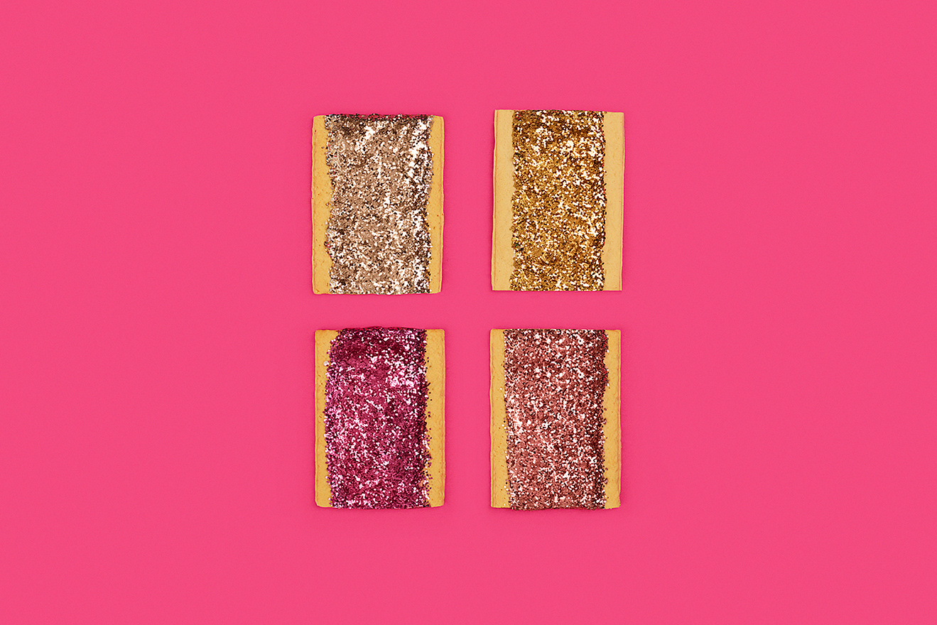Four rectangular treats covered in glitter on a vivid pink background, arranged in a square pattern, creating a visually striking composition.