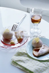 Pastries and a glass of amber liquid styled on white tabletops with plates, a fork, and a checkered napkin.
