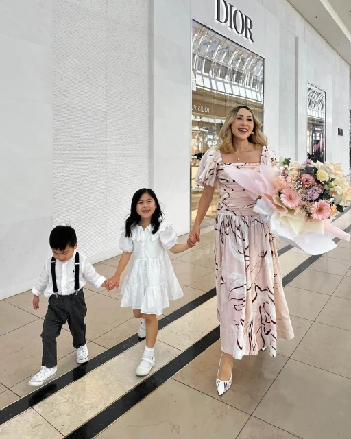 Stylish mother and two children walking out of a DIOR store with a large flower bouquet, capturing a lifestyle moment.