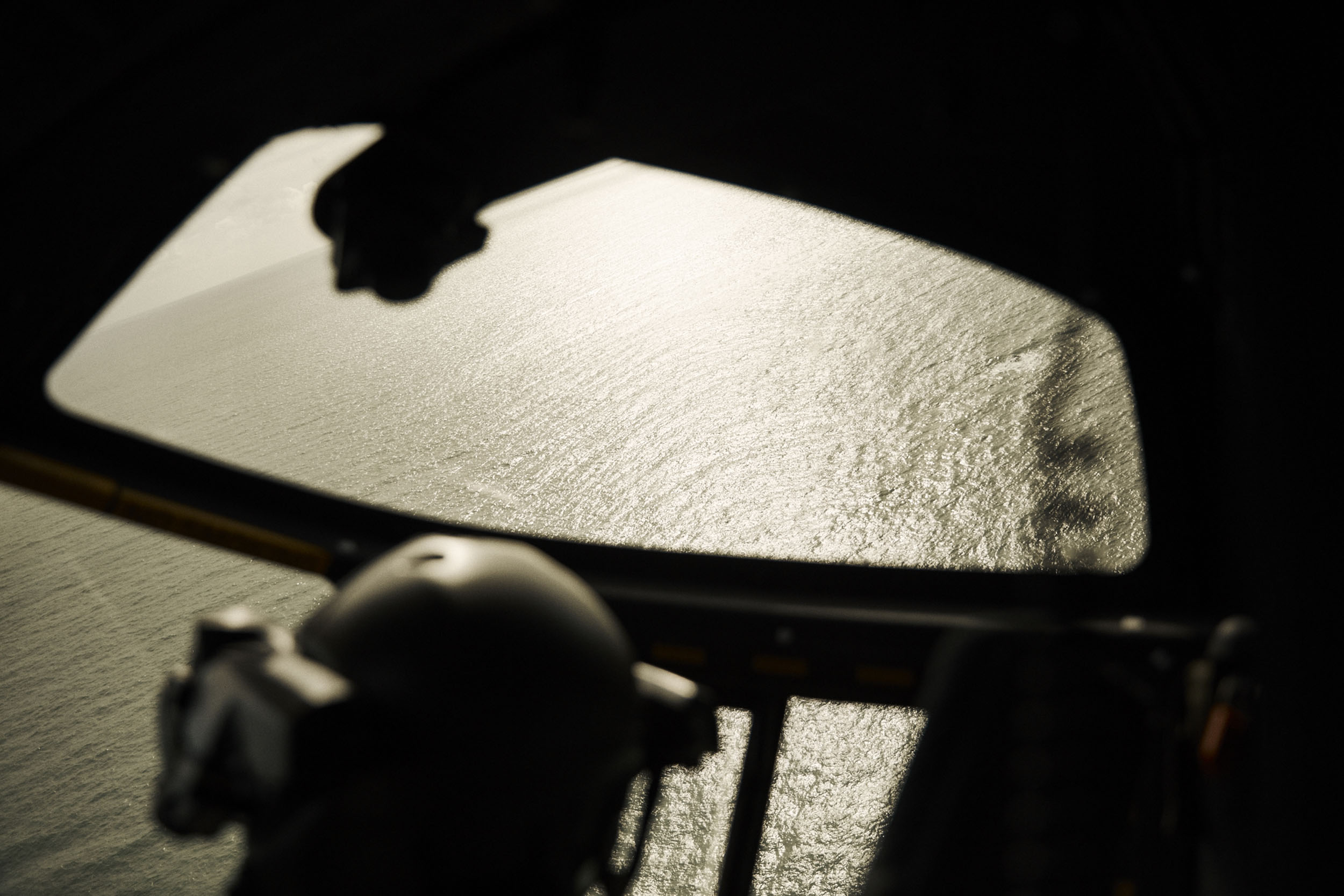 Cockpit view of ocean water reflecting light through the windshield, with dark interior elements in silhouette.