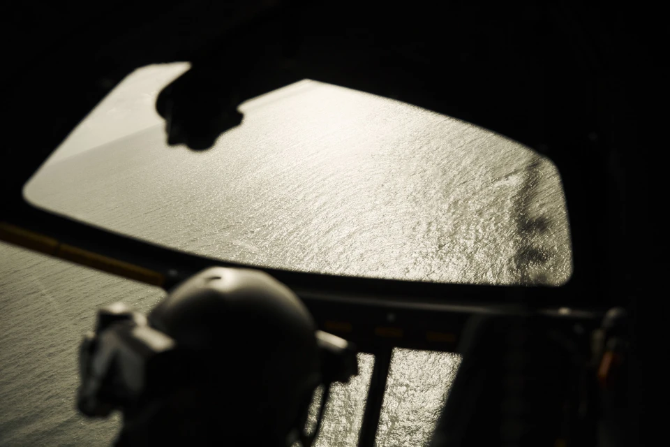 Cockpit view of ocean water reflecting light through the windshield, with dark interior elements in silhouette.