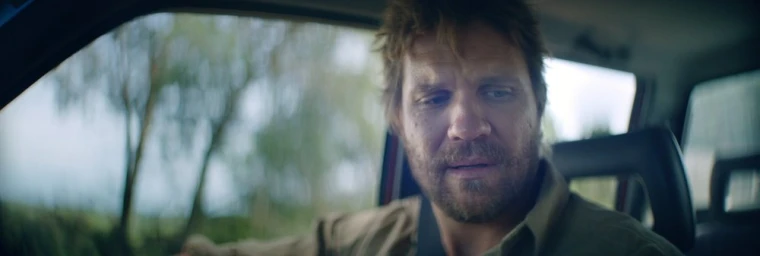 Close-up portrait of a man with a beard sitting inside a car looking downward